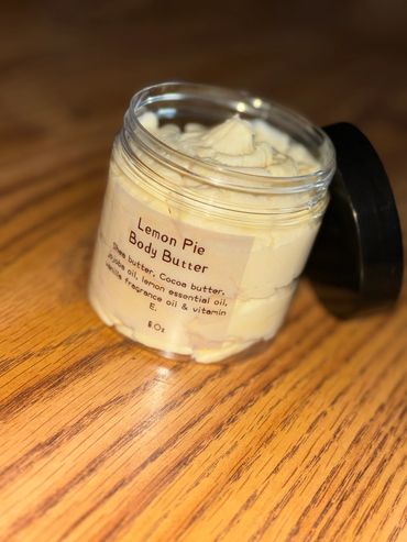 Open jar of lemon pie scented body butter on wooden surface.