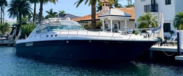 Dark-hull motor yacht docked at a waterfront home, pre-purchase marine survey