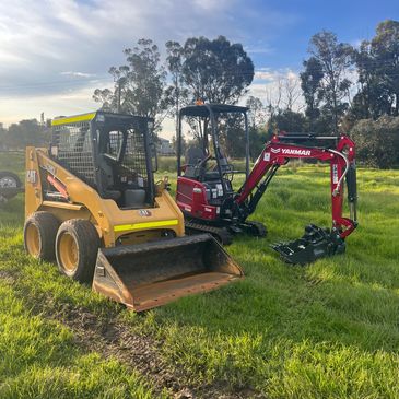 Two construction machines parked on grassy field.