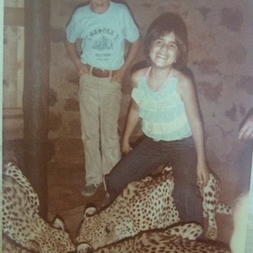 Two children interact closely with four cheetahs indoors.