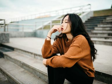Woman sitting thoughtfully on outdoor steps.