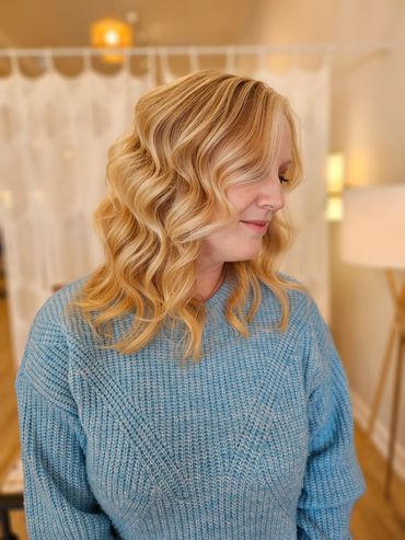 Woman with wavy blonde hair in a blue sweater.