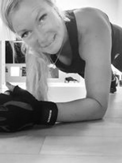 Woman smiling while doing a plank exercise indoors.