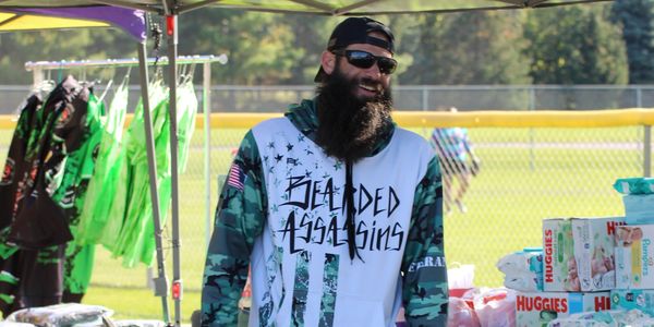 Man with a beard and sunglasses at an outdoor booth.