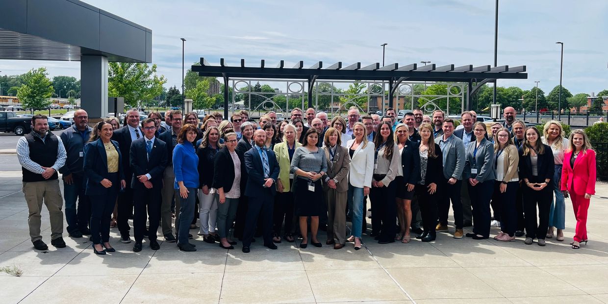 A large group of professionally dressed people posing outdoors.