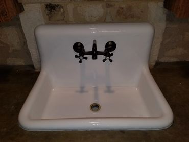 Vintage white porcelain sink with dark bronze faucet and handles. Curing after being resurfaced/refinished.