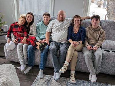 husband Mike & wife Tami sitting on couch with their 4 kids daughter Sage & sons Mason Jaxon & Lucas