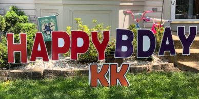 Large colorful letters spelling 'HAPPY BDAY KK' on a lawn.