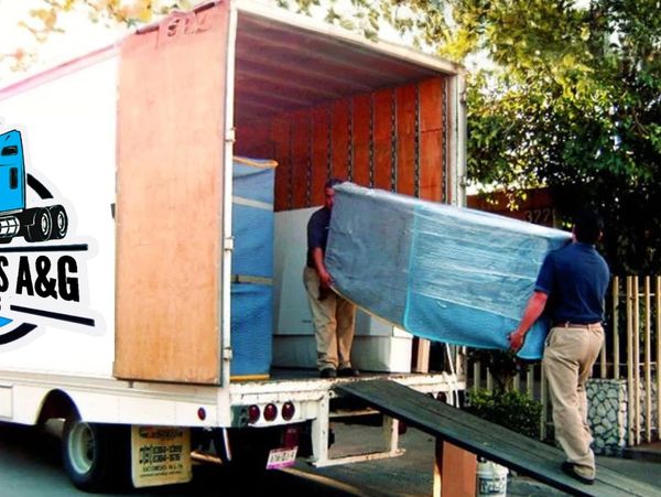 Dos hombres cargando un mueble en una camioneta de mudanza.