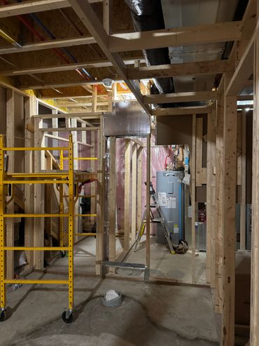 Basement under construction with wooden framing and a water heater.