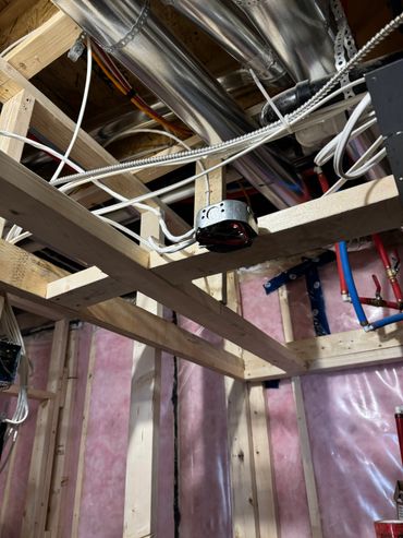 Exposed wooden framing and electrical wiring in a building under construction.