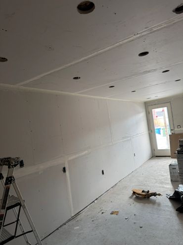 Room under construction with drywall installed and tools scattered.