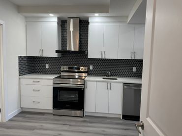 Modern kitchen with white cabinets and black hexagonal tile backsplash.