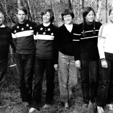 Group of six people standing outdoors with trees in the background.