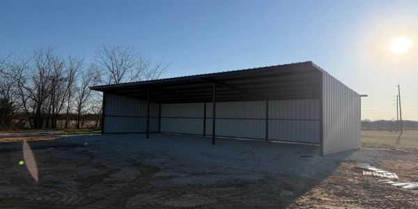 Large metal carport structure under clear sky during sunset.
