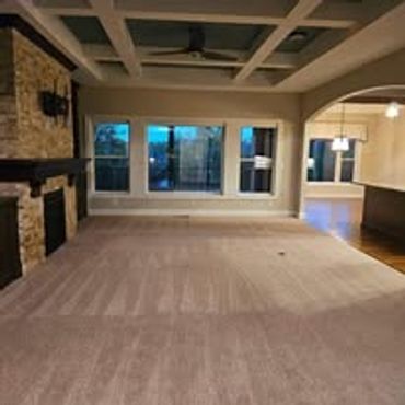 Spacious empty living room with carpet and stone fireplace.
