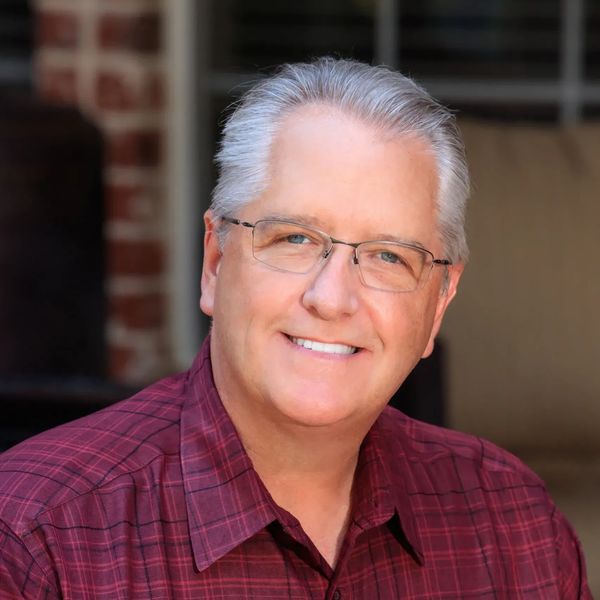 Smiling middle-aged man wearing glasses and a red plaid shirt.