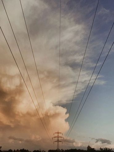 Electric power lines stretch across a dramatic sunset sky.