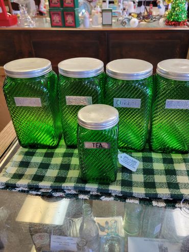 Set of vintage green glass jars labeled for kitchen staples.