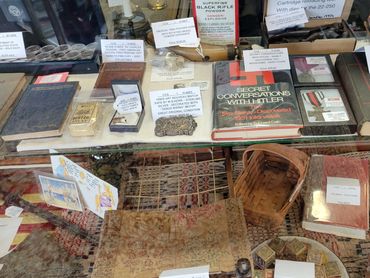 Display case with vintage books, collectibles, and antique items with price tags.
