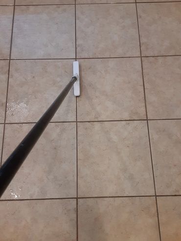 Using a brush to agitate the grout lines before the extraction process for a deep tile cleaning job.