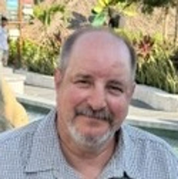 Smiling middle-aged man with a beard and mustache.