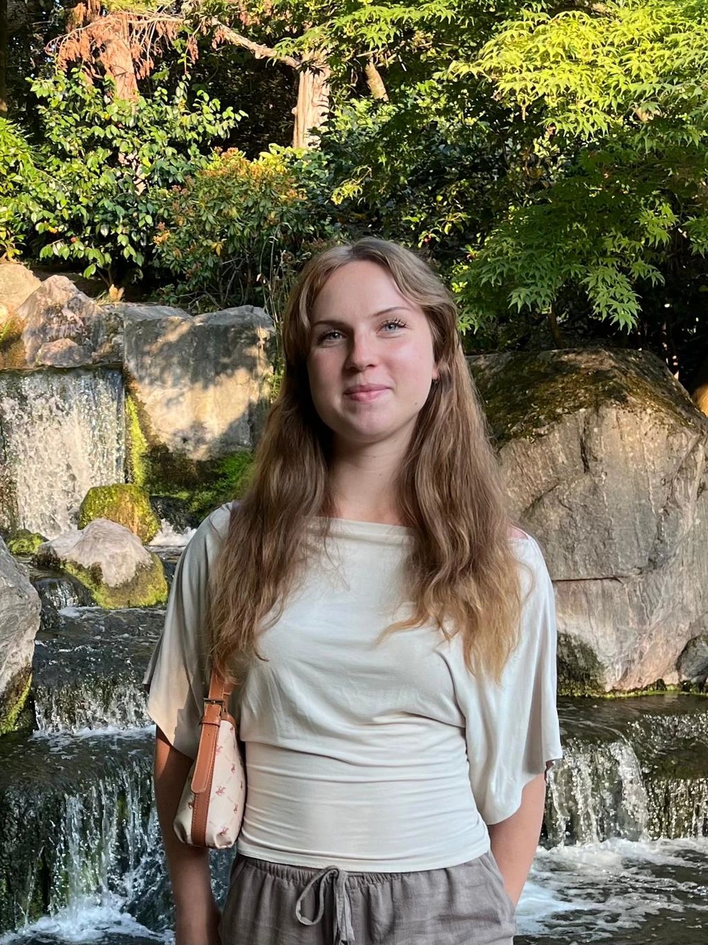 Young woman smiling in front of a waterfall.