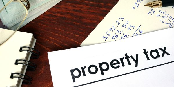 Image depicting a notebook and financial figures with the wording "Property Tax"
