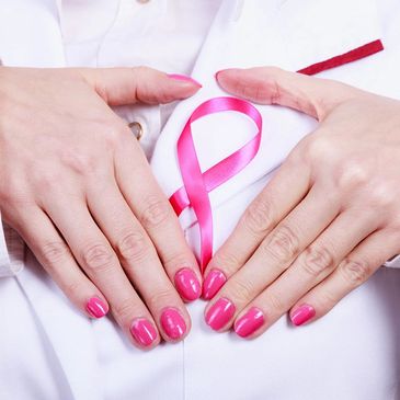 Image of hands surrounding a pink breast cancer ribbon on their white coat lapel