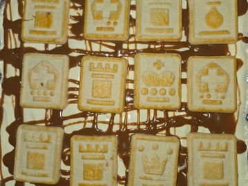 Cream-filled biscuits with various embossed designs on a chocolate drizzle background.