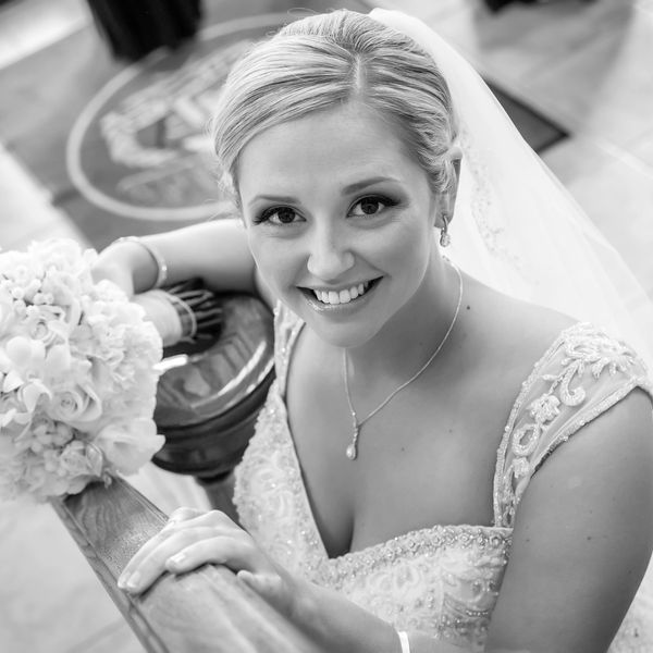 black and white wedding portrait of a bride holding her bouquet, looking up and smiling