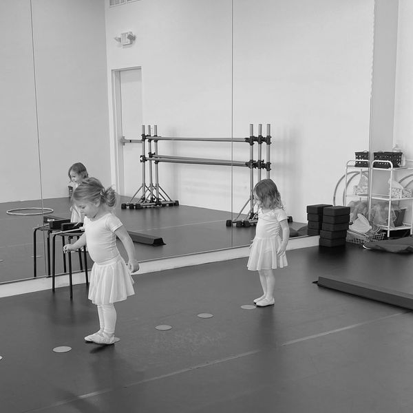 Two young girls practicing ballet in a dance studio.