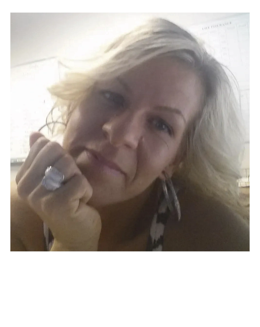 Close-up of a woman with blonde hair resting her chin on her hand.