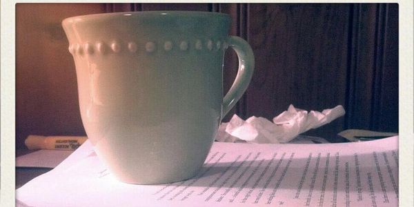 A green coffee mug on top of a rough draft