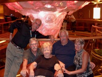 Group of five adults posing indoors with decorative background.