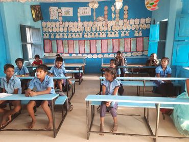 Students sitting on new benches in an elementary school classroom.