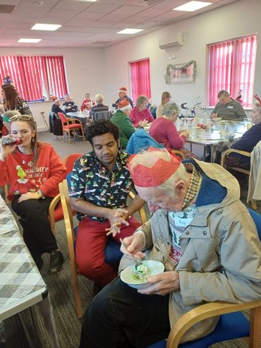 A diverse group enjoying a festive meal in a cheerful community room.