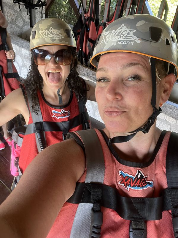 Two women in helmets and harnesses excited for an adventure.