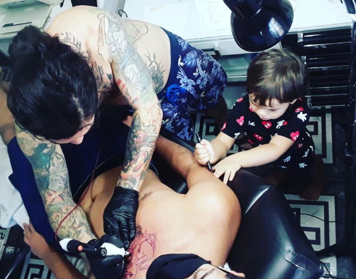 Tattoo artist tattooing a client with his son, best tattoos in miami only at empire ink studios