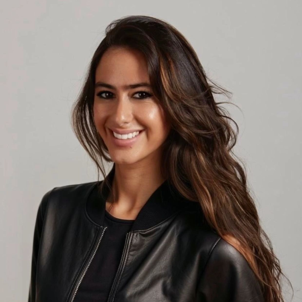 Smiling woman with long hair wearing a black leather jacket.