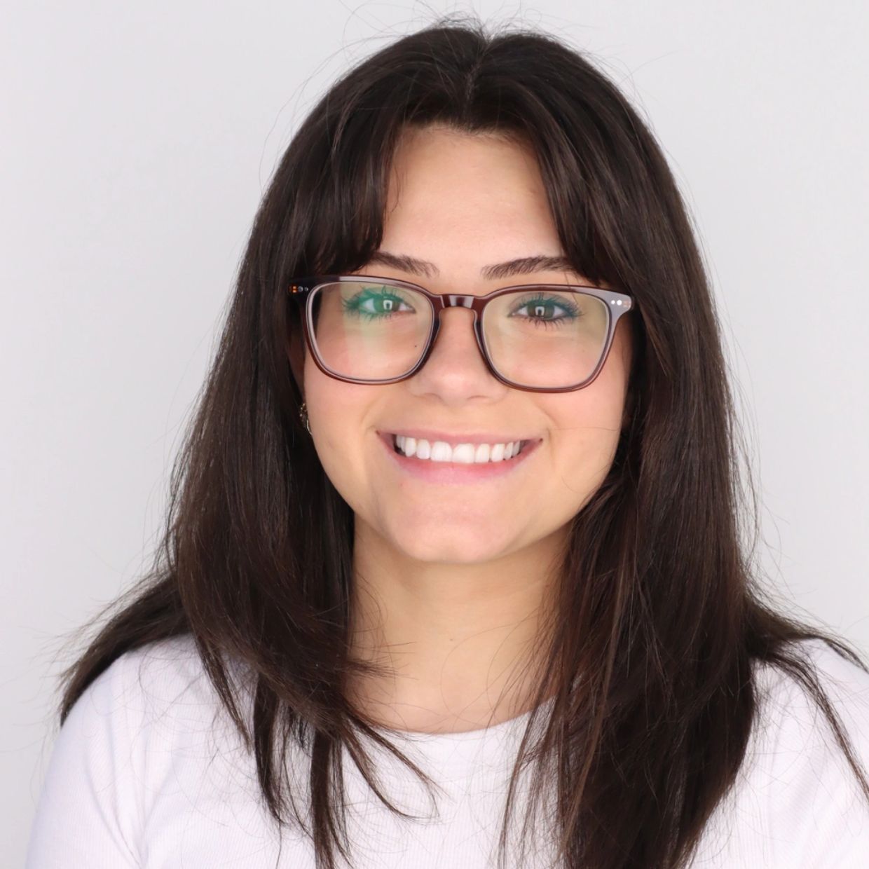 Young woman with glasses smiling against a white background.