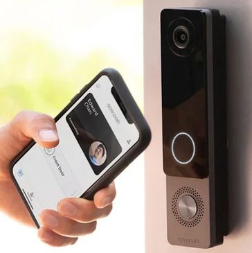 Person using smartphone to unlock a smart doorbell.
