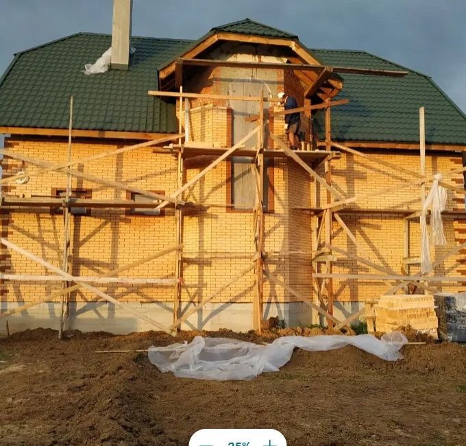 Construction workers building a brick house with wooden scaffolding.