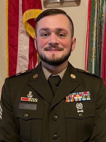 Smiling military serviceman in dress uniform with medals and ribbons.