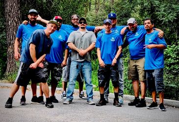 Group of men posing outdoors in blue shirts.