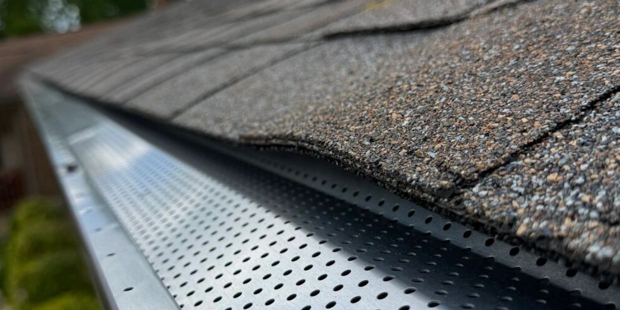 Close-up of a house roof with a metal gutter guard installed.