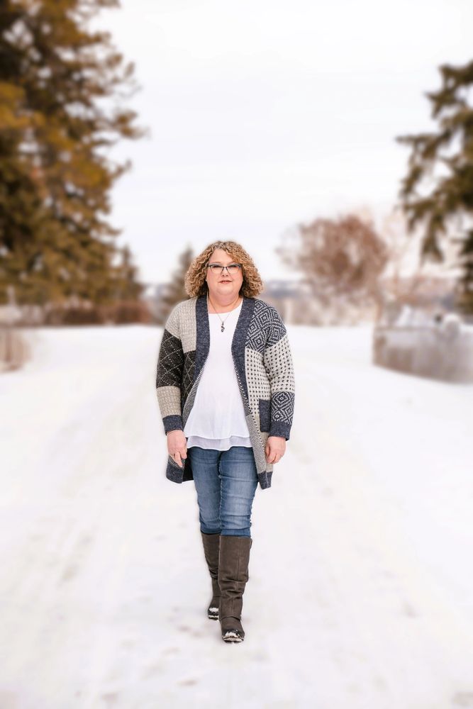 Woman walking confidently on a snowy path wearing a patterned cardigan and boots.