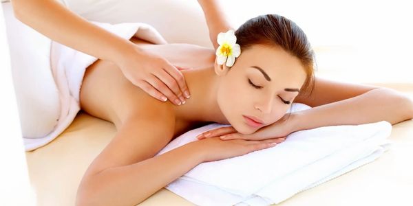Woman receiving a relaxing back massage with a flower in her hair.