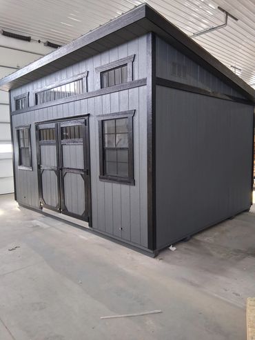 A modern gray shed with black trim inside a garage.