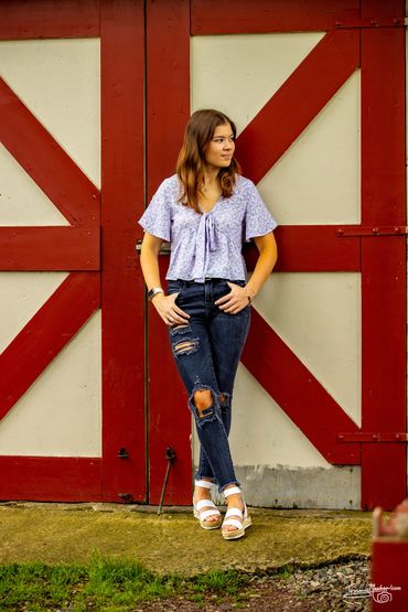 Young woman in casual outfit standing against a red and cream door.